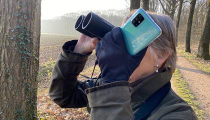 Teller in actie met smartphone en kijker